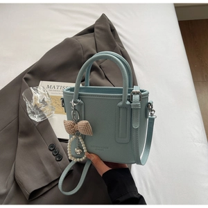 Detail of light blue lychee pattern bucket bag with pearl heart charm and bow decor