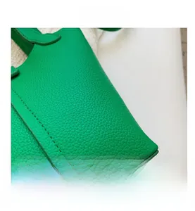 Macro shot of green lychee leather texture and precision stitching on this bucket bag