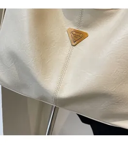 Detailed close-up of white leather tote with fine texture and triangular metal logo
