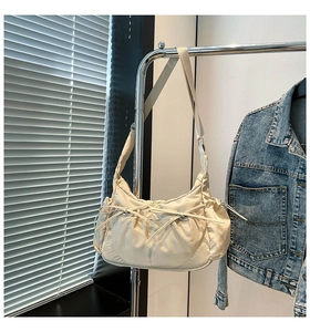 Détail du sac demi-lune en nylon crème avec texture à cordon et bandoulière réglable