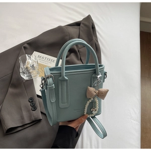 Close-up of light blue leather bucket bag with bow charm and pearl heart detail