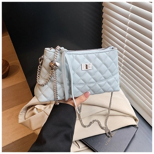Détail du sac seau bleu clair matelassé avec bandoulière chaîne argentée et boule métal