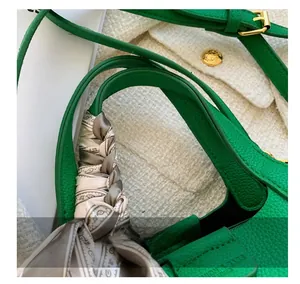Close-up of green lychee leather handbag handle with decorative silk scarf and gold hardware