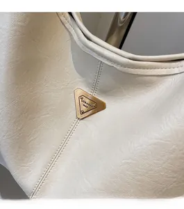 Macro shot of off-white lychee texture leather handbag with gold triangle metal logo plate
