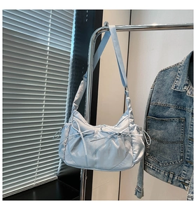 Détail d'un sac en nylon bleu clair avec nœuds décoratifs et plis à cordon