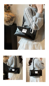 Detail einer glänzenden schwarzen Schultertasche aus Lackleder mit Markenaufnäher