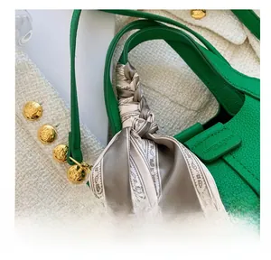 Detail of lychee pattern leather bucket bag with decorative silk scarf and fashion logo