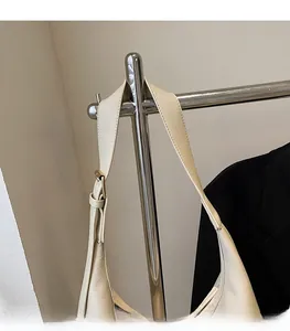 Close-up of adjustable beige leather shoulder strap with gold metal buckle detail