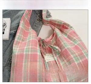Détail du sac cabas en toile à carreaux rose et vert avec étiquette et ruban décoratif