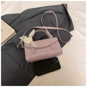 Dettaglio della piccola borsa lavanda con fiocco di pizzo a cuore e finitura in pelle