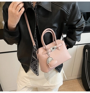 Detailopname van roze litchi-leer met hartvormige hanger en zilveren draaisluiting accent