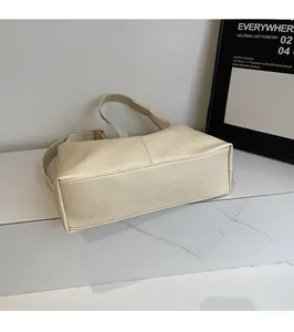 Detail view of cream leather tote bag with fine litchi texture on a marble surface