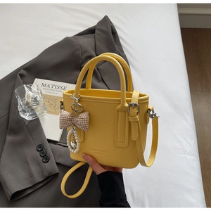 Detail of yellow lychee texture bucket bag with pearl chain and bow charm detail