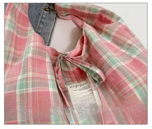 Détail du sac en toile à carreaux rose et vert avec nœuds décoratifs et étiquette tissée interne