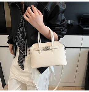 Detail van de witte leren tas met lychee-textuur en zilveren metalen draaisluiting