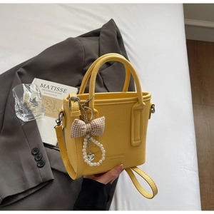Detailed view of yellow bucket bag with lychee texture and pearl heart charm