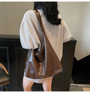 Detail of a brown pleated tote bag showing the textured synthetic leather and metal accents