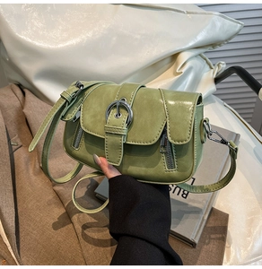 Detail of green PU leather crossbody bag featuring silver buckle and glossy finish texture
