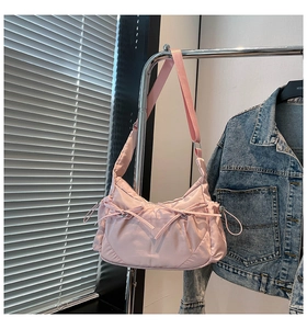 Détail d'un sac bandoulière rose en nylon avec nœud coulissant sur un support métal