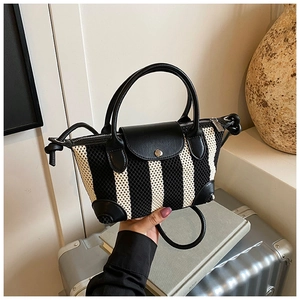 Dettaglio di una mini borsa tote a righe con manici in pelle nera e chiusura a pressione