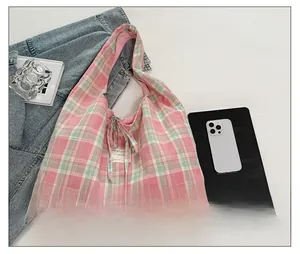Vue à plat d'un sac cabas en toile à carreaux rose et vert avec détail de nœud brodé