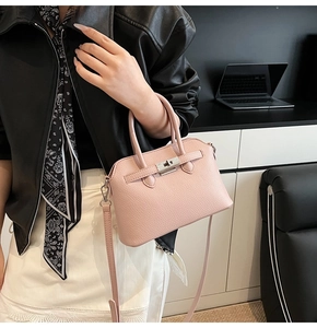 Detail van de roze handtas met litchi-textuur en gepolijste zilveren draaisluiting