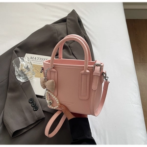 Detail of pink lychee grain leather bucket bag with pearl chain and bow decoration