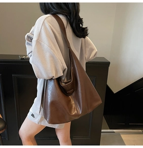 Close-up of a dark brown soft leather hobo bag with polished finish and metal logo