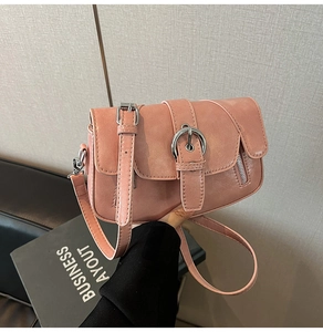Detail showing pink faux leather texture and large metal buckle on the crossbody bag