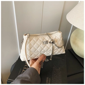 Détail de sac matelassé blanc avec fermoir rotatif argenté et bandoulière chaîne