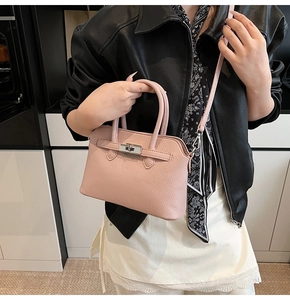 Detail van roze lychee lederen handtas met zilveren draaisluiting en schouderriem