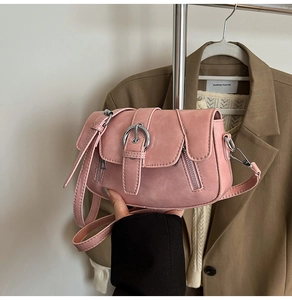 Detail view of pink saddle bag with large metal buckle and side zipper accents
