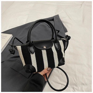Dettaglio di una borsa in maglia a righe con manici in pelle e chiusura a bottone