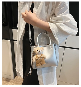 Detail view of silver handbag featuring metallic luster and a cute bear bag charm accessory