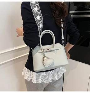 Detail van lichtgroene lychee lederen Kelly tas met geborduurde band en hartvormige hanger