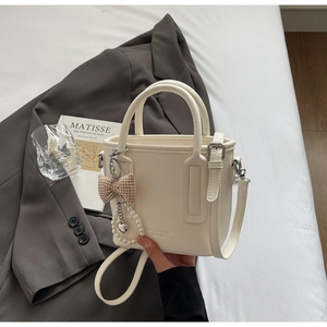 Close-up of cream white lychee leather texture with pearl charm and ribbon detail
