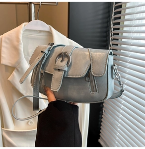 Detail of light blue textured leather crossbody bag with silver buckle and zipper accents
