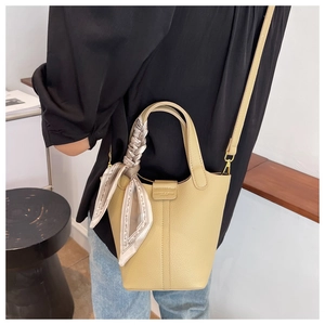 Litchi texture leather bucket bag with silk scarf on handle worn as crossbody