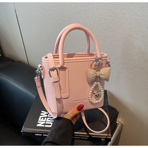 Close-up of pink litchi pattern bucket bag featuring pearl charms and bow detail
