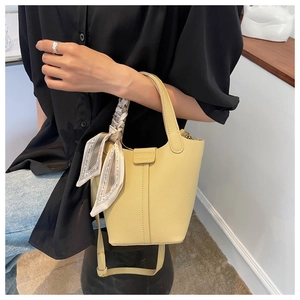 Detail of yellow lychee leather bucket bag with printed silk scarf handle and slim strap