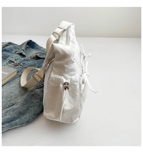 Détail du sac à bandoulière en nylon blanc avec nœud latéral et cordon de serrage