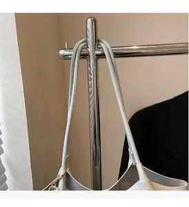 Detail of lychee textured leather bucket bag with metal ring pendant hanging on a rack