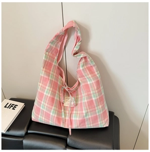 Détail du sac cabas en toile à carreaux verts avec nœud décoratif et étiquette tissée
