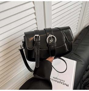Close-up of vintage black crossbody bag with double belt buckles and silver ring detail