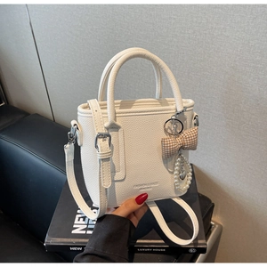 Close-up of high-quality white lychee texture leather bucket bag with pearl heart charm