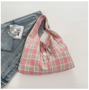Détail du sac en toile à carreaux rose et vert avec fermeture à nouer et étiquette
