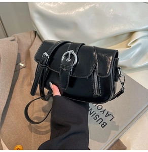Detail of vintage black crossbody bag featuring a silver round buckle and adjustable strap