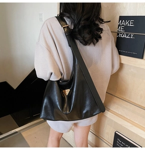 Detail view of the black leather tote bag with silver logo and adjustable wide shoulder strap