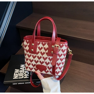 Detail of red heart jacquard mini tote bag with leather trim on a wooden staircase