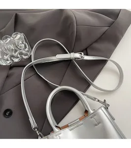 Close-up of silver crossbody bag with smooth metallic finish and adjustable strap